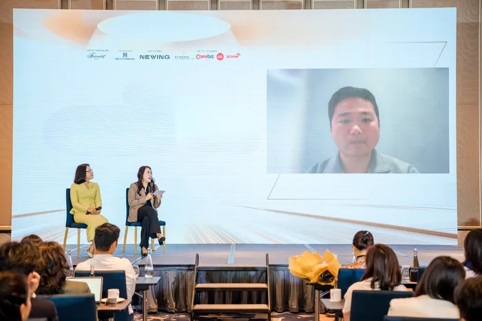 Chandee Zhuang appearing by video on a stage screen